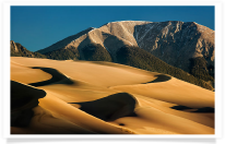 Shadowed Dunes and Ridges with Mountain Backdrop